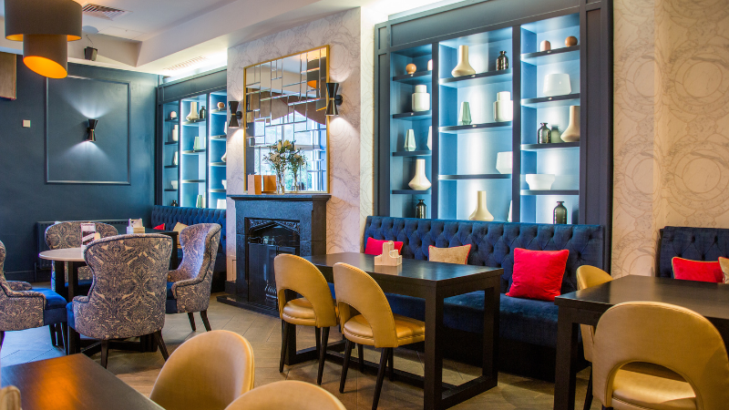 Blue and navy decor surrounding a cosy fireplace with comfrotable seating in a bar setting.